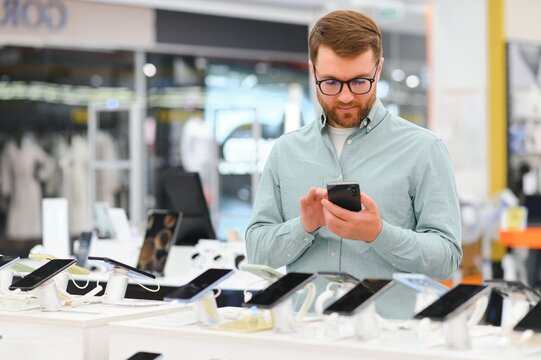 guy in an electronics store chooses a cell phone to buy