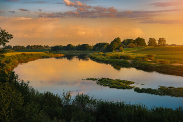 Beautiful sunset in countryside with river and grain fields