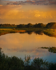 Beautiful sunset in countryside with river and grain fields