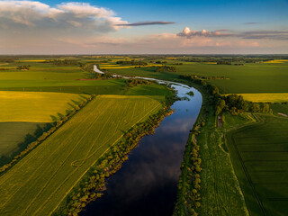 Aerial view of beautiful sunset in countryside with river and grain fields