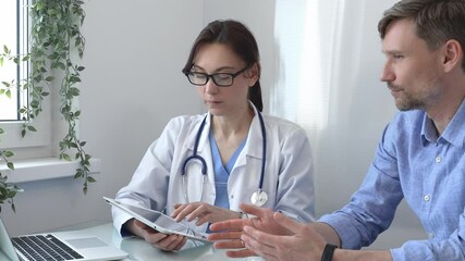 Female doctor using a digital tablet for explaining test results to a male patient during a consultation in a bright, modern medical office. Medicine concept - Powered by Adobe