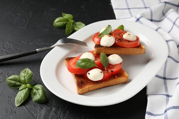 Tasty sandwiches with mozzarella cheese, tomatoes and basil on dark textured table, closeup