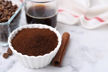 Instant coffee powder in bowl, cinnamon stick, beans and drink on white marble table, closeup. Space for text