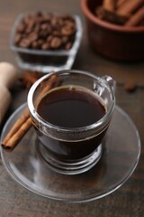 Refreshing coffee in cup and cinnamon stick on wooden table, closeup