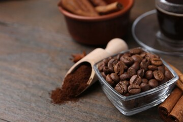 Roasted beans, instant coffee powder and cinnamon sticks on wooden table, closeup. Space for text