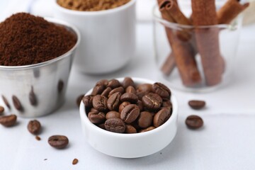 Roasted beans, different types of instant coffee and cinnamon sticks on light table, closeup