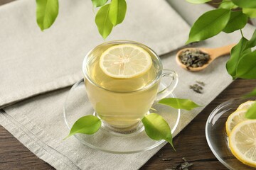 Refreshing green tea with lemon and leaves on wooden table, closeup