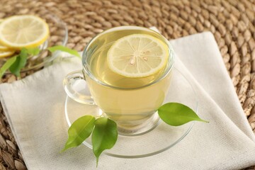 Refreshing green tea with lemon and leaves on table, closeup