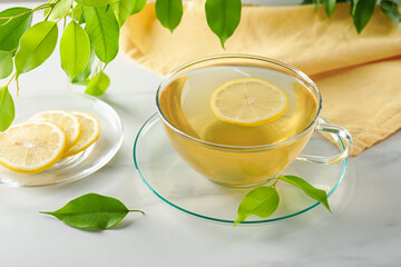 Refreshing green tea with lemon and leaves on white marble table, closeup