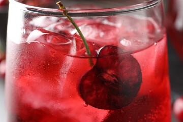 Tasty cherry soda with ice cubes and berry in glass, closeup