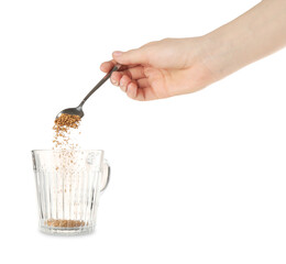 Woman adding granulated instant coffee from spoon into glass cup on white background, closeup