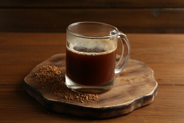 Tasty coffee in cup and instant granules on wooden table, closeup