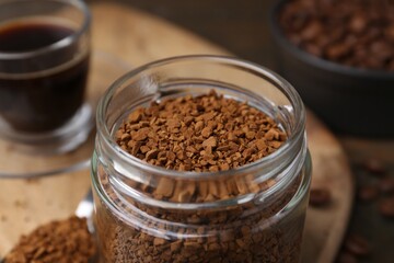 Instant coffee in glass jar, hot drink and beans on table, closeup