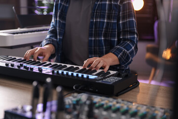 Man working with MIDI keyboard at table, closeup