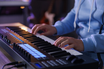 Obraz premium Man working with MIDI keyboard at table in home studio, closeup