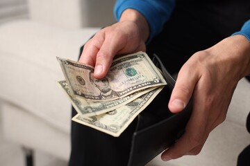 Man putting money into wallet indoors, closeup