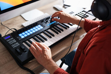 Man working with MIDI keyboard at wooden table indoors, above view
