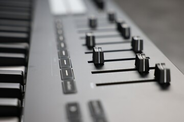 MIDI keyboard with faders on table, closeup