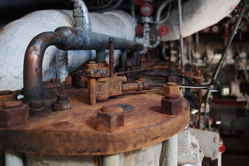 A detailed close-up of old and rusty industrial machinery, likely from a factory or an engine room. 