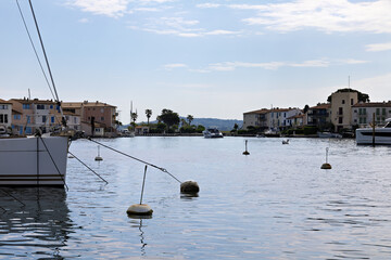 Port Grimaud harbor from the water with ships, yachts, pier and shops as well as residential...
