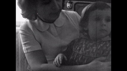 Old film, Mother wiping little child face after eating, feeding at home. Caring mother takes care of baby girl. Parent toddler bonding together. Vintage family love archive. Archival retro 1960s - Powered by Adobe