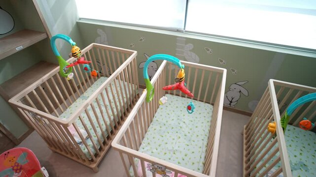 Empty cribs with colorful baby mobiles waiting for babies at a daycare in Karachi
