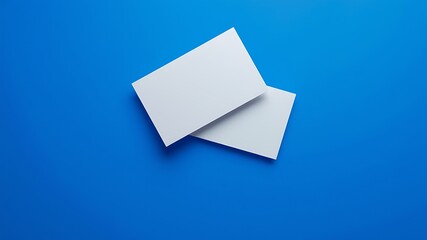 Clean white rectangular cards or business cards elegantly overlapping on a vibrant solid blue background with soft shadows
