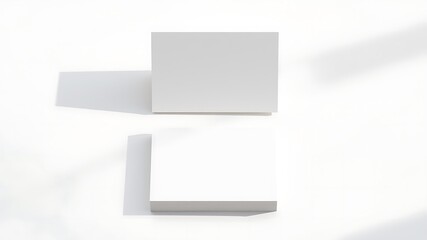 Two blank white square cards or brochures casting soft shadows on a clean white background top down view