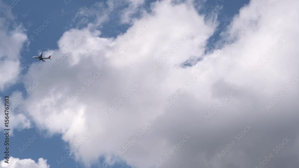 Poster a plane glides smoothly through a clear sky filled with fluffy clouds, showcasing a serene afternoon