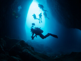 group of divers exploring inside an underwater cave, concept of scuba diving and underwater...