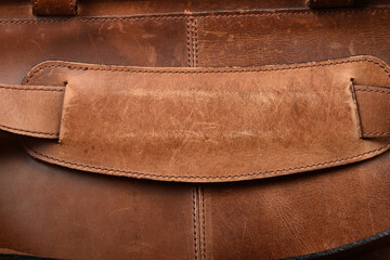 A close-up shows a stitched brown leather shoulder strap pad on a textured brown leather bag