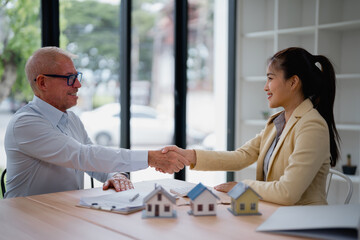 Real estate agent and customer shaking hands after finalizing a contract for a new house,...