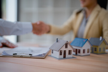 Real estate agent and customer shaking hands after signing contract for new house purchase,...