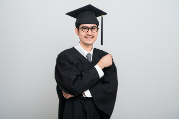 A young man in a graduation gown and cap smiles at the camera, striking a confident pose to celebrate his academic achievement on graduation day.