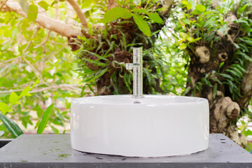Bathroom sink in a tropical garden. Outdoor faucet and sink in the green barrel.