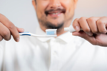 Happy bearded man putting toothpaste on a toothbrush bathroom. Personal hygiene concept.