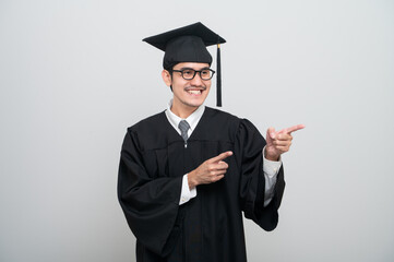 A young man in a graduation gown and cap smiles at the camera, striking a confident pose to celebrate his academic achievement on graduation day.