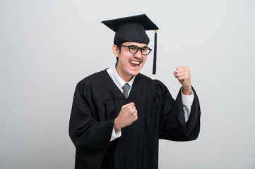 A young man in a graduation gown and cap smiles at the camera, striking a confident pose to celebrate his academic achievement on graduation day.