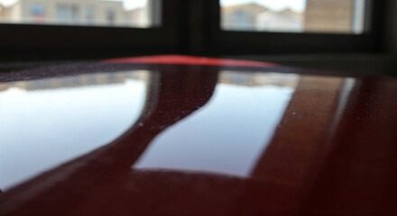 Reflections on a Dark Red Surface Near a Window