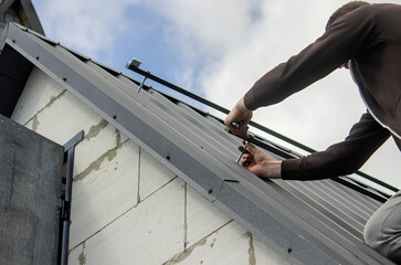 A man is installing solar panel mounts on the roof. Selective focus