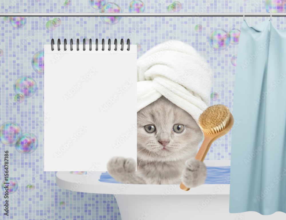 Aufkleber Cute kitten with towel on it head takes the bath at home and shows blank notepad. Empty space for text
