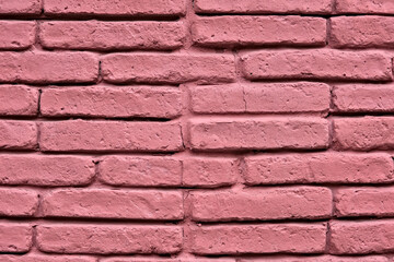 Close-up of a pink brick wall with rough texture and visible mortar lines, showing an urban, artistic, and colorful architectural detail.