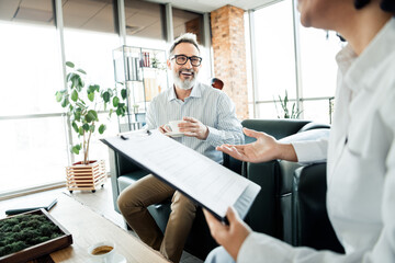 Mature Professionals Collaborating in a Stylish Office Setting Engaged in a Business Discussion Amid a Bright Environment