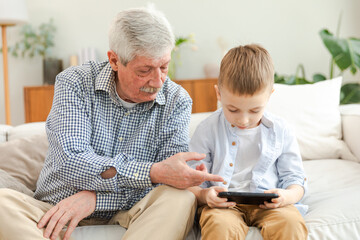 Happy family at home. Old senior man grandfather boy grandson enjoying time together watching video...