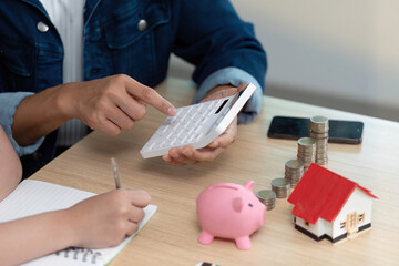 Couple Using Calculator for Financial Planning. Discussing savings and investments with piggy bank.