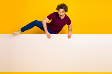 Energetic young man with curly hair posing on a vibrant yellow background, showcasing stylish...
