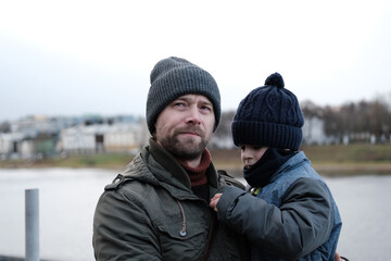 Father and son walking down on sidewalk together. Portrait of a handsome middle-aged man with...