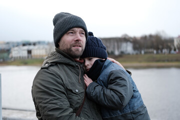 Father and son walking down on sidewalk together. Portrait of a handsome middle-aged man with...