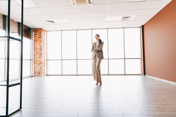 Fototapeta premium Young specialist Businesswoman standing confidently in an open modern workspace
