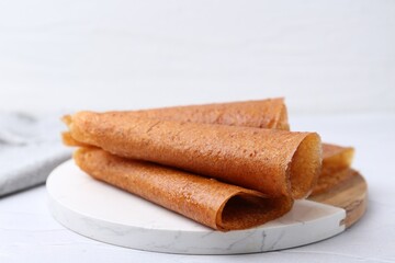 Delicious fruit leather rolls on white table, closeup
